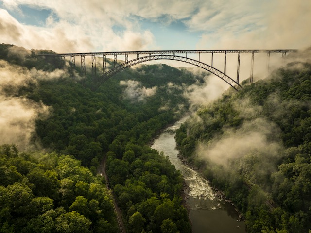 High-level view of the New River Gorge with clouds and fog in the valley.