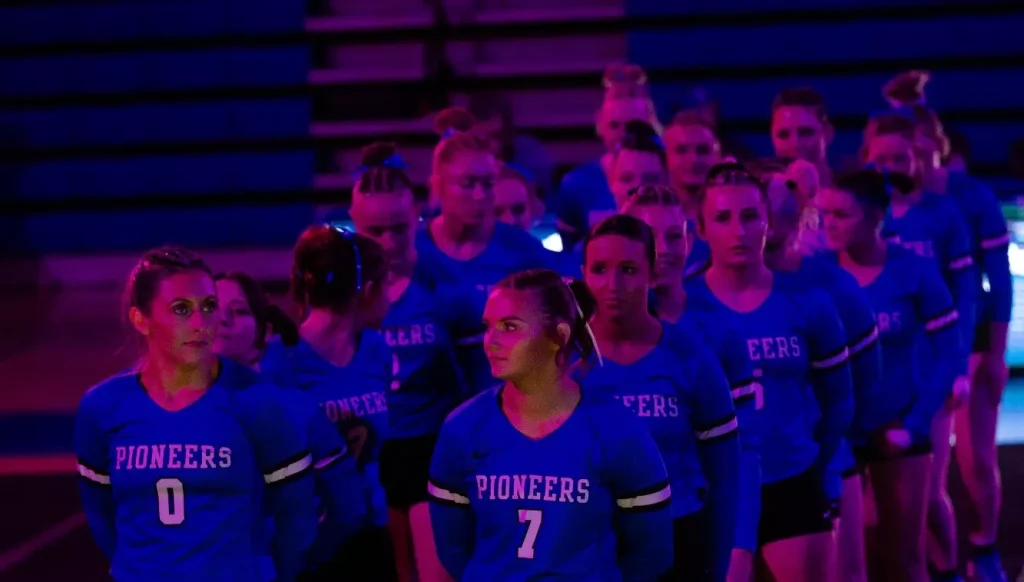 Glenville State acrobatics team members standing in two lines and wearing blue long-sleeved jerseys. 