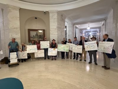 Advocates for Blackwater Canyon stand with handmade signs inside the West Virginia state capitol.