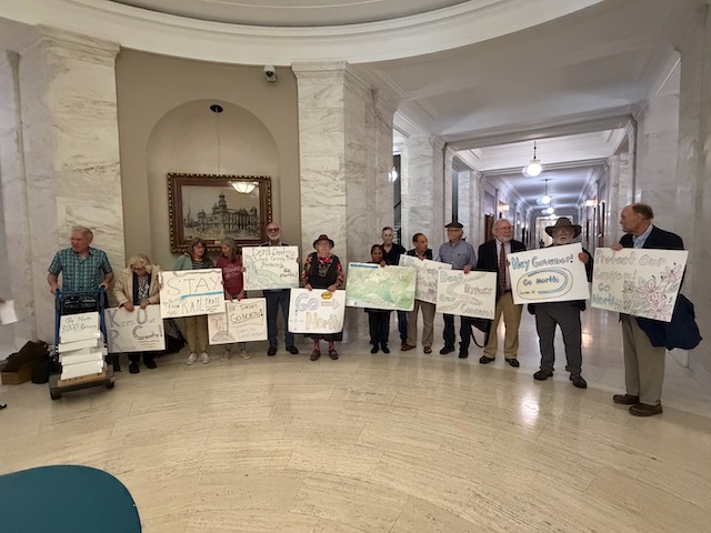 Advocates for Blackwater Canyon stand with handmade signs inside the West Virginia state capitol.